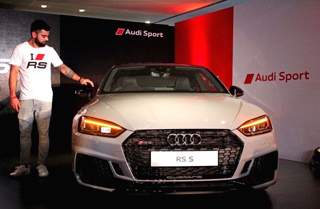 Virat Kohli standing beside the Audi RS5 performance coupe at an Audi Sport event.
