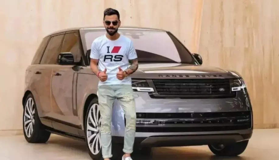 Virat Kohli posing in front of his Range Rover Vogue luxury SUV.