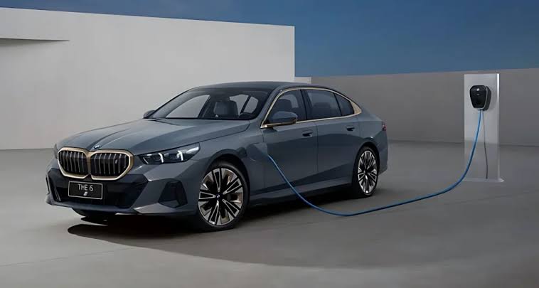 BMW i5 LWB electric sedan connected to a wall charging unit